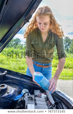 Zdjęcia stock: Dutch Woman Filling Car Reservoir With Fluid In Bottle