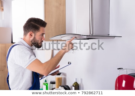 [[stock_photo]]: Handyman Checking Kitchen Extractor Filter