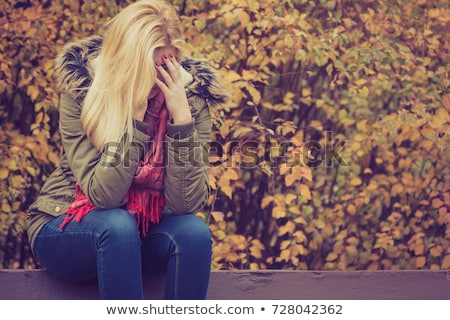 Foto stock: A Sad Woman In Park During Autumn Weather Hiding Face In Hand Feeling Terrible Depressed