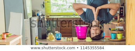 Stok fotoğraf: A Man Stands On His Hands Upside Down In The Kitchen Banner Long Format