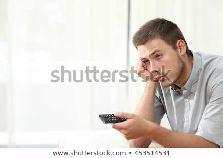 Stock foto: Bored Man Watching Tv And Zapping Sitting On A Couch At Home