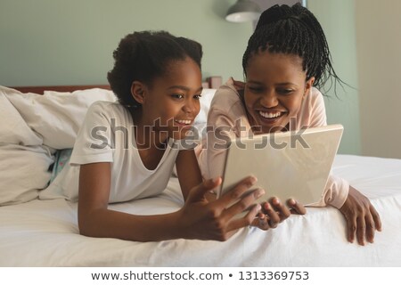 Stock foto: Front View Of Happy African American Mother And Daughter Lying On Bed And Using Digital Tablet In Be
