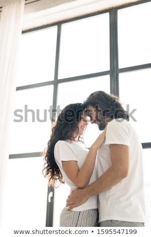 Imagine de stoc: Young Affectionate Smiling Couple In White T Shirts Standing Close To Each Other