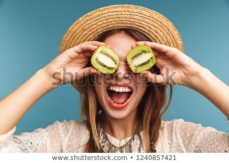 Stok fotoğraf: Happy Pretty Woman Posing Isolated Over Blue Wall Background With Kiwi