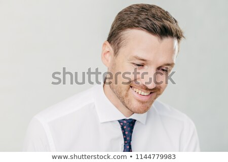 Stock foto: Joyful Male Corporate Worker In Elegant White Shirt Looks Happily Down Remembers Something Pleasan