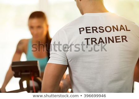 Сток-фото: Personal Trainer With Young Woman On Cycling Machine At The Gym