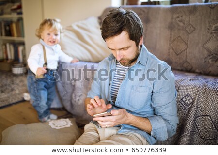 Сток-фото: Father Holding A Baby And Texting On His Mobile