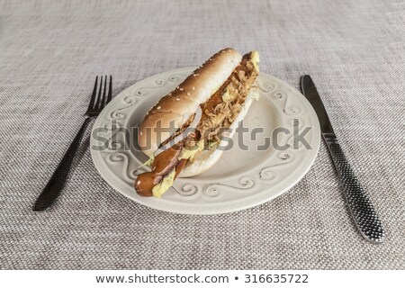 Stockfoto: Fresh Tasty Hot Dog With Fried Onions And Fresh Lettuce With Mustard On A Porcelain Plate With Fork