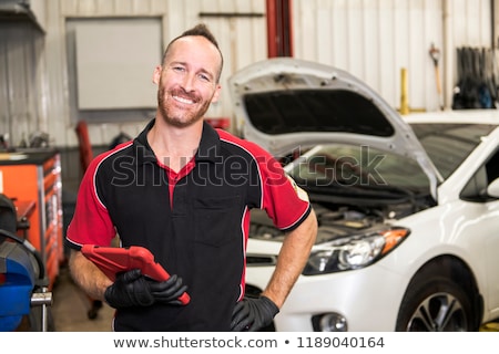 Foto d'archivio: Handsome Mechanic Based On Car In Auto Repair Shop With Tablet On Hand