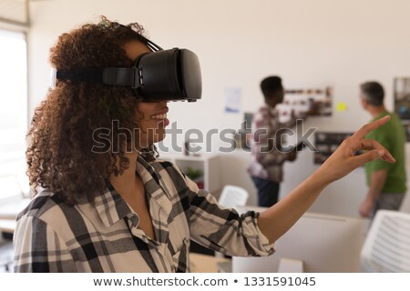 Stok fotoğraf: Side View Of Beautiful Mixed Race Female Executive Using Virtual Reality Headset In Modern Modern Of