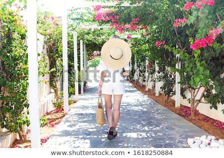 Foto d'archivio: Blond Girl In Straw Hat In Front Of Pink Bougainvillea Flowers