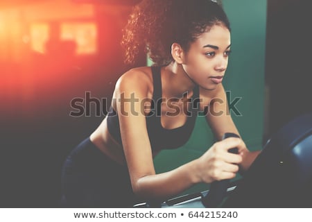 Foto stock: Young Beautiful Woman Training By Riding A Bicycle In A Gym