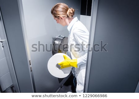 [[stock_photo]]: Janitor Woman Changing Paper In Public Toilet