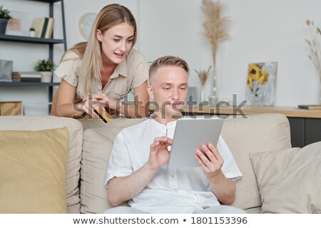 Stock foto: Casual Young Couple Sitting On Comfortable Couch And Scrolling In Touchpad