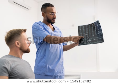 Foto stock: Radiologist In Blue Uniform And His Patient Discussing X Ray Of Broken Joint