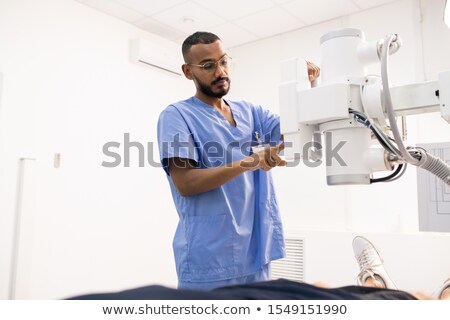 Foto stock: Bearded Young Mixed Race Man In Blue Uniform Using New Medical Equipment