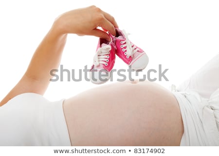 Stock fotó: Woman Is Holding Little Pink Shoes Over Pregnant Belly