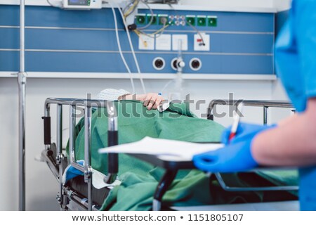 Nurse Writing Down Data On Patient In Recovery Room Of Modern Hospital Foto stock © Kzenon