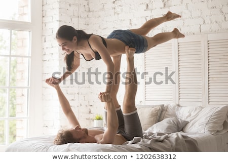 Foto stock: Smiling Young Couple Doing Yoga On Bed