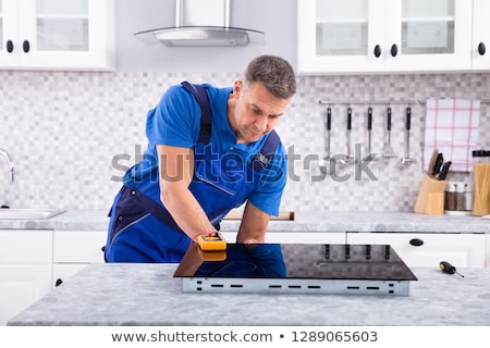 Stock photo: Mature Repairman Examining Induction Stove