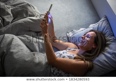 Stockfoto: Pretty Middle Aged Woman Using Her Tablet Computer Before Sleep