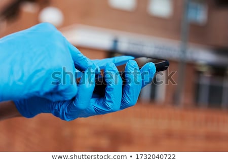 Foto stock: Man Wearing Latex Gloves Using His Smartphone