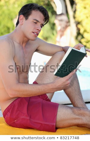 Stock photo: Man Sat By Pool Reading Book