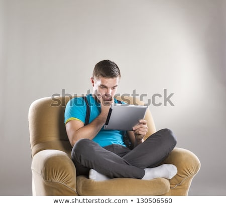 Foto stock: Boy With A Tablet Pc Sitting On A Chair