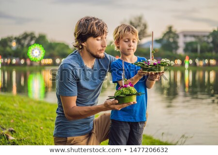 Сток-фото: Father And Son Tourists Holds The Loy Krathong In Her Hands And Is About To Launch It Into The Water
