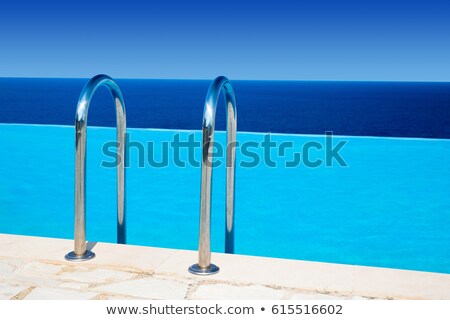 [[stock_photo]]: Rails To Luxury Blue Swimming Pool Near The Sea And Sunny Sky Above