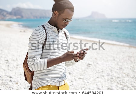 Stock photo: Male Tourist Using Mobile Phone At Seaside On Summer Holiday