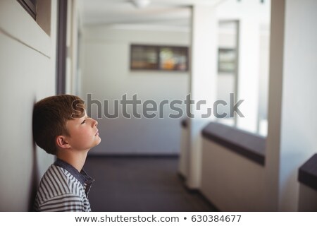Stok fotoğraf: Close Up Of Sad Schoolboy Leaning Head Against Wall In Corridor Of School