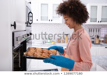 Stok fotoğraf: Woman Removing Tray With Baked Croissants From Oven