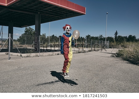 Foto stock: Scary Clown With A Golden Balloon Outdoors