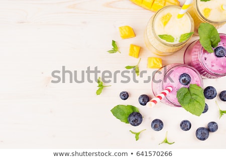 Stockfoto: Freshly Blended Yellow Mango Fruit Smoothie In Glass Jars With Straw Mint Leaves Mango Slices Top