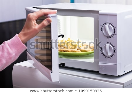 Stockfoto: Woman Heating Fried Food In Microwave Oven