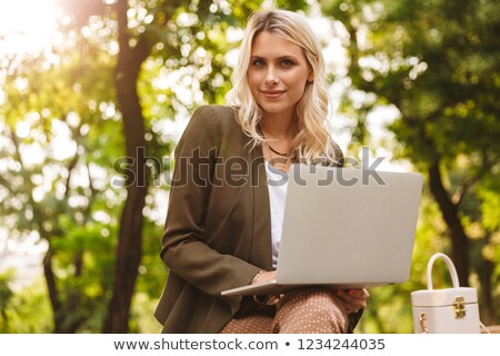 Foto stock: Image Of Elegant Woman 20s Using Silver Laptop While Sitting On