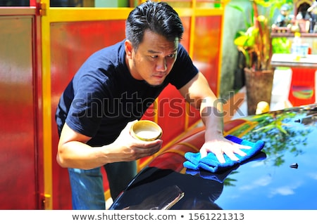 Stockfoto: Man At Work Cleaning Automobile At Car Wash Waxy