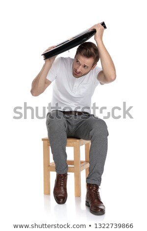 Stock photo: Scared Young Casual Man Defending Himself With His Briefcase