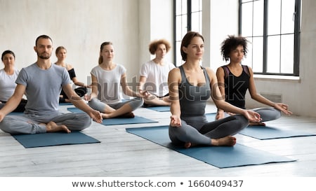 Stockfoto: Young Serene Cross Legged Woman Sitting On Mat In Gym After Training