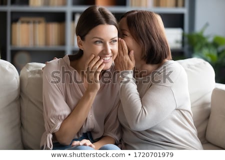 Stock fotó: Adult Daughter Whispering To Senior Mother At Home