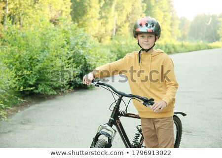Stok fotoğraf: Cheerful Woman In Protective Helmet With Bicycle Standing On Road