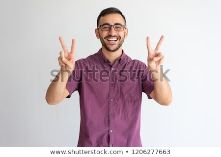 Сток-фото: Smiling Young Casual Man Making Victory Sign