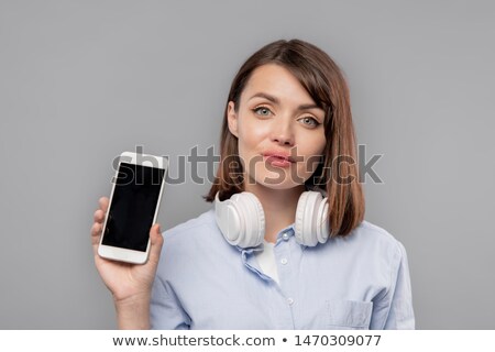 Foto stock: Pretty Girl With Headphones Showing You Advert Or Promo On Smartphone Screen