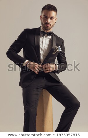 Foto stock: Seated Elegant Man In Tuxedo Fixing His Hairstyle