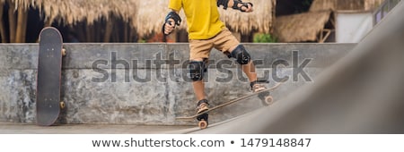 Stok fotoğraf: Athletic Boy In Helmet And Knee Pads Learns To Skateboard With In A Skate Park Children Education