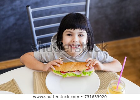 Stockfoto: Cute Black Hair Little Girl Eating Sandwich At Home