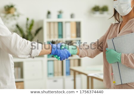 Stockfoto: Two People Holding Hands Wearing Surgical Gloves