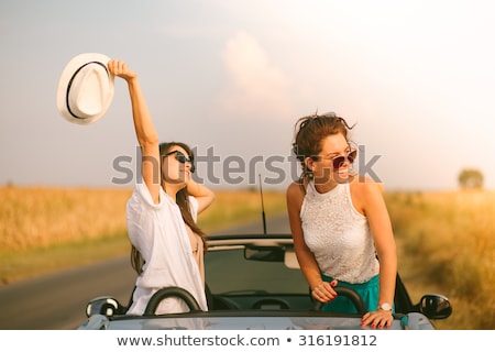 Stok fotoğraf: Two Young Happy Girls Having Fun In The Cabriolet Outdoors