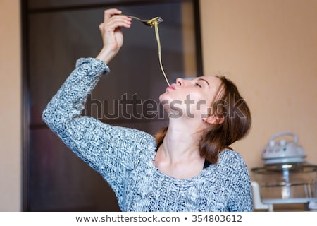 Stok fotoğraf: Amusing Attractive Young Woman Eating Pasta In Kitchen